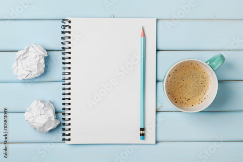 Fotografie, Obraz Coffee mug, clean notebook, pencil and crumpled paper on blue rustic table from