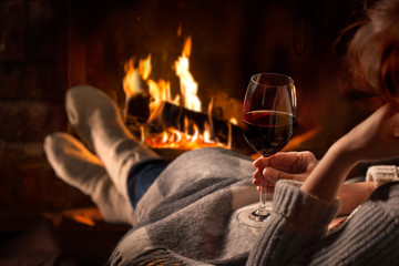 Wall Mural - Woman resting with wine glass near fireplace