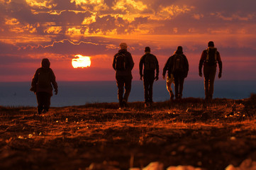 people reach the top walking at sunset