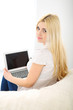 © rogerphoto - Happy woman doing online shopping at home . Close- up of a hand holding a credit card next to a laptop