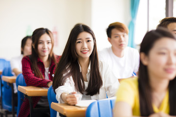 smiling female college student sitting  with classmates