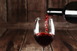 Red wine is pouring from a bottle into a glass