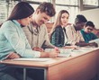 © Nejron Photo - Multinational group of cheerful students taking an active part in a lesson while sitting in a lecture hall.