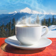 A cup of hot coffee on a background of mountains.