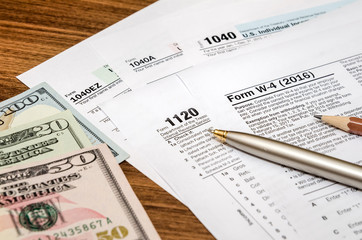 tax form w4, 1040, 1120 with pen and us dollar