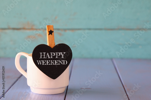 Fotografía cup of coffee and little heart shape chalkboard with the phrase: HAPPY WEEKEND