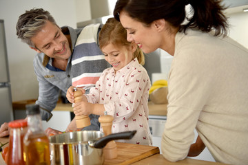 Parents with child cooking together at home