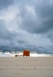 dramatic cloudy minimalist beach view with a wooden dressing cabin. changing room