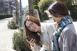 © Monet - Two women looking at a smart phone with a laugh