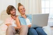 © WavebreakmediaMicro - Cute couple using laptop sitting on the couch