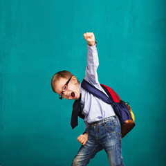 smiling little boy with big backpack jumping and having fun