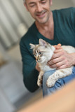 Fototapeta Koty - Man at home cuddling beautiful cat