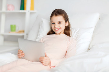 Poster - happy girl lying in bed with tablet pc at home