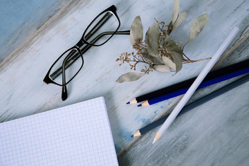 Workspace with notebook glasses and blue color pencils on the wooden vintage table background copy space
