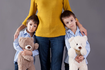 Wall Mural - Sad little children, boys, hugging their mother at home, isolate