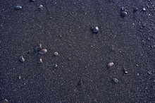 Wet Pebbles On Black Beach Sand Background