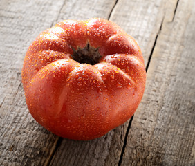 ripe tomato with drops of water on wooden background
