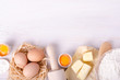 Ingredients for baking croissants - flour, wooden spoon, rolling pin, eggs, egg yolks, butter served on white background.