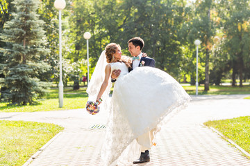 wedding couple hugging, the bride holding a bouquet of flowers,  groom embracing her