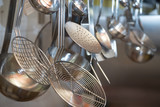 Fototapeta Zachód słońca - strainers ladles and kitchen accessories hanging
