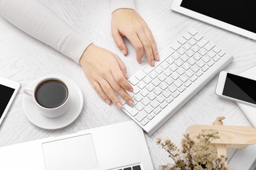 Canvas Print - Concept of using electronics. Businesswoman works at office. Computer, laptop, tablet, cup of coffee and other things on the table. Top view