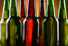 Green And Brown Glass Bottles Of Beer On Dark Lighted Background, Close Up