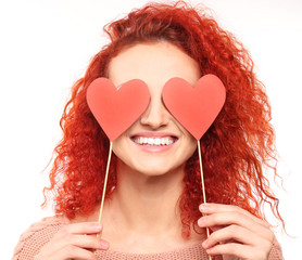 Poster - Red-haired young woman holding paper hearts near eyes, isolated on white