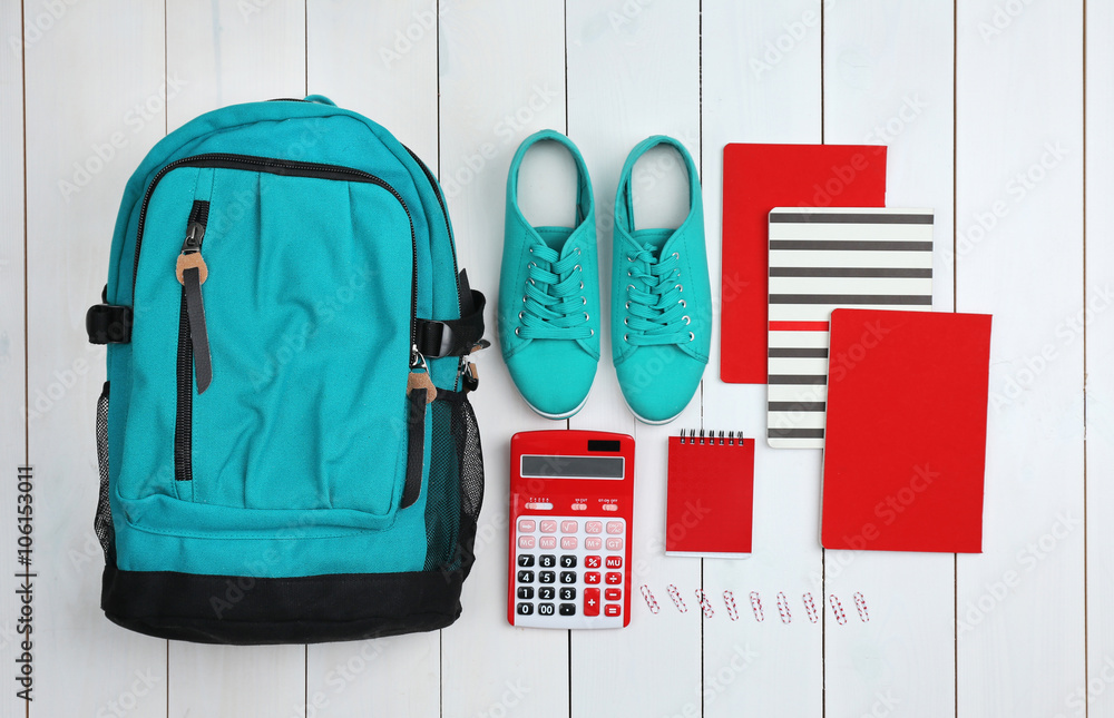 Backpack and school supplies on wooden background, close up. Top view.