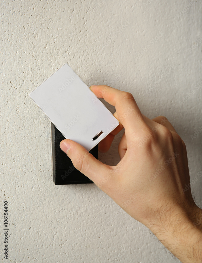 Security alarm with male hand on wall background, closeup