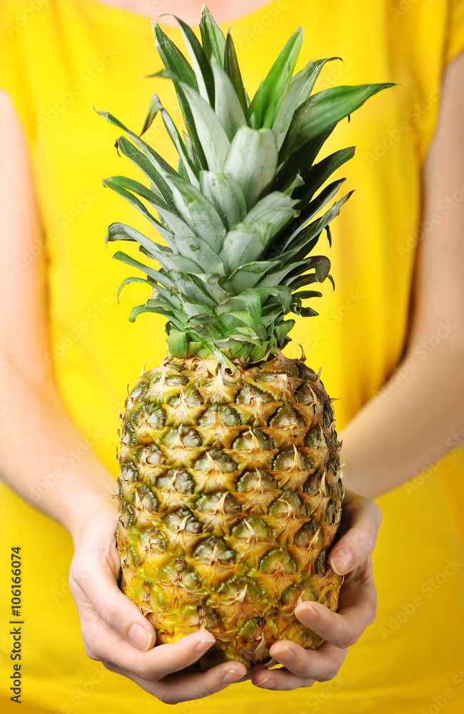 Woman holding ripe pineapple, close up