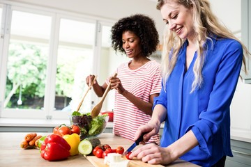 cheerful female friends preparing food at table