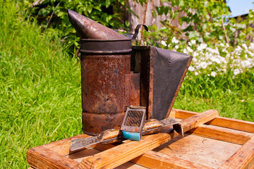 Old smoker and other tool of the beekeeper on the wooden box.