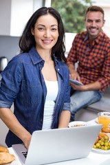 Wall Mural - Young woman using laptop and man using digital tablet