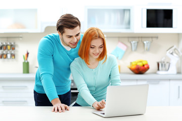 Canvas Print - Young couple using laptop on the kitchen