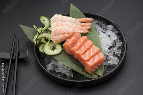 Naklejka samoprzylepna Łososiowy sashimi na bambusowej liście i lodzie nad czarnym tłem
