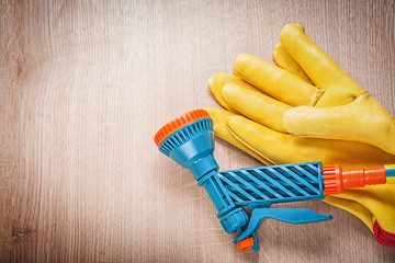 Leather protective gloves with garden hand spray gun on wooden b