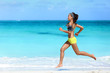 © Maridav - Fitness runner woman running on beach listening to music motivation with phone case sport armband strap. Sporty athlete training cardio barefoot with determination under summer sun.
