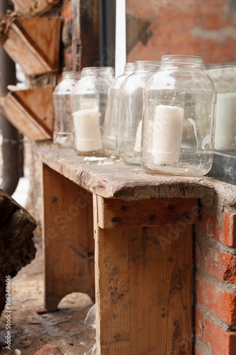 White Big Candles In Glass Jars On A Narrow Retro Wooden Table