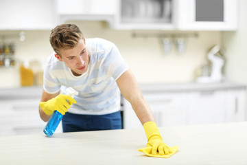 Poster - Handsome man cleaning kitchen with spray and rag