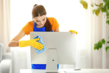 Canvas Print - Young woman cleaning computer monitor at workplace in the office