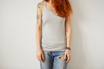 Wall Mural - Girl wearing grey blank t-shirt standing on the background of a white wall.