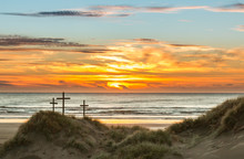 Three Crosses On A Sand Dune With A Sunset Over The Sea.