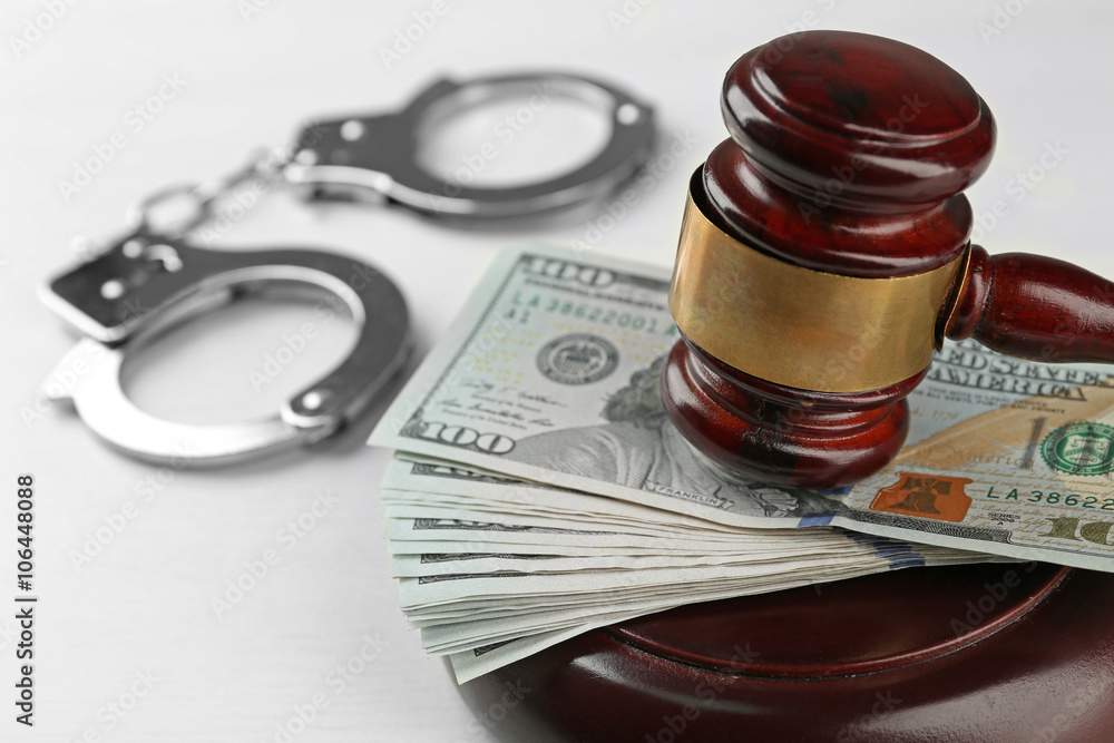Law gavel with dollars and handcuffs isolated on white