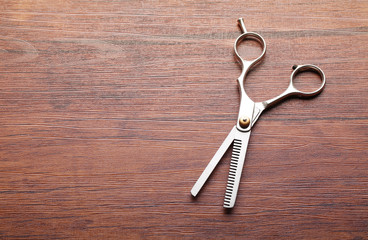 Wall Mural - Professional metal scissors lying on the wooden table, close up