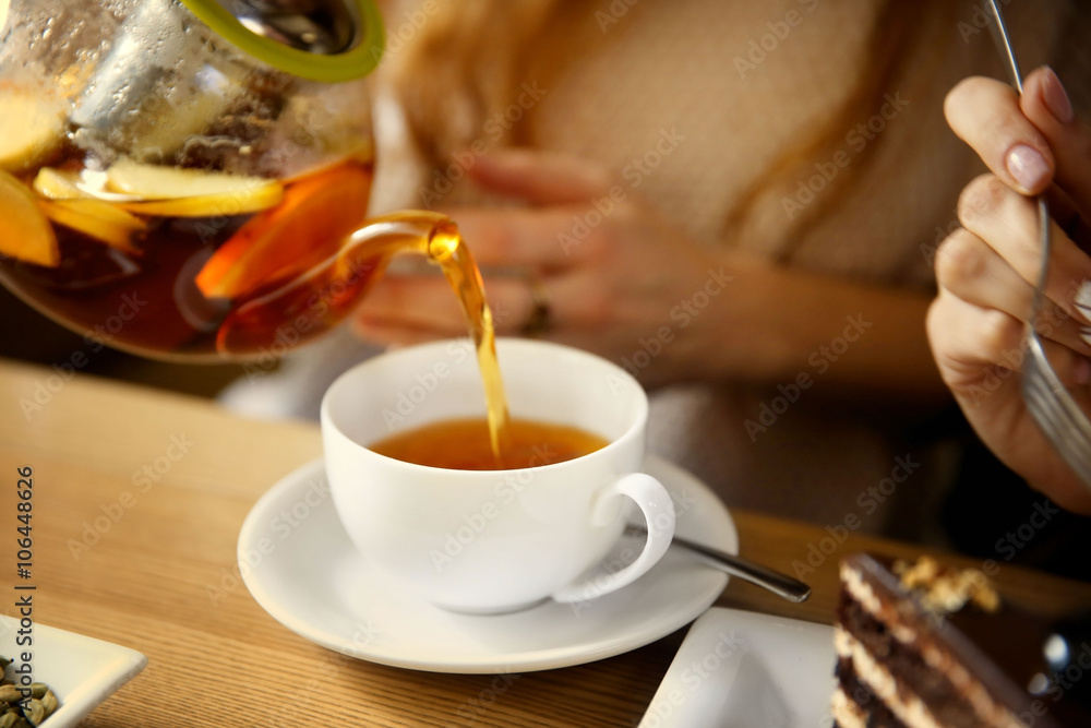 Pouring tea into a white cup in cafe or restaurant