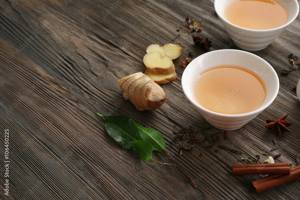 Two cups of brewed tea with ginger and spices on wooden table