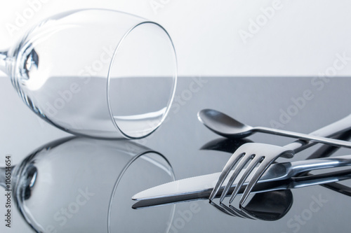 Zdjęcie XXL Nóż, widelec, łyżeczka i kieliszek do wina na błyszczącym, odbijającym blacie stołu