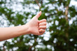 man hand showing thumb up finger on blur nature background