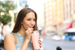 Woman eating a milkshake in the street