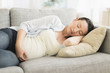 © JGI/Tom Grill/Blend Images - Pregnant Japanese woman napping on sofa